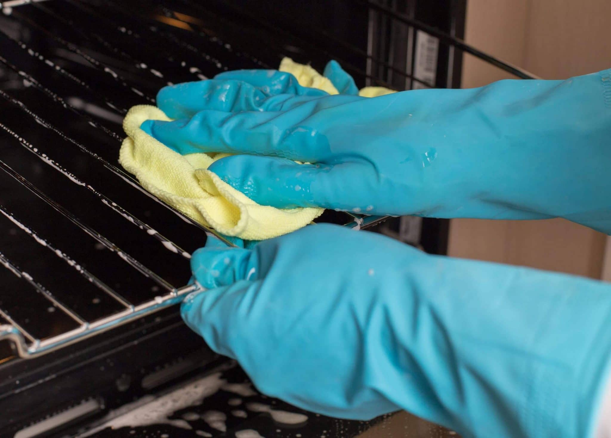 Oven wire cleaning Close up of hands with protective gloves cleaning wire in oven