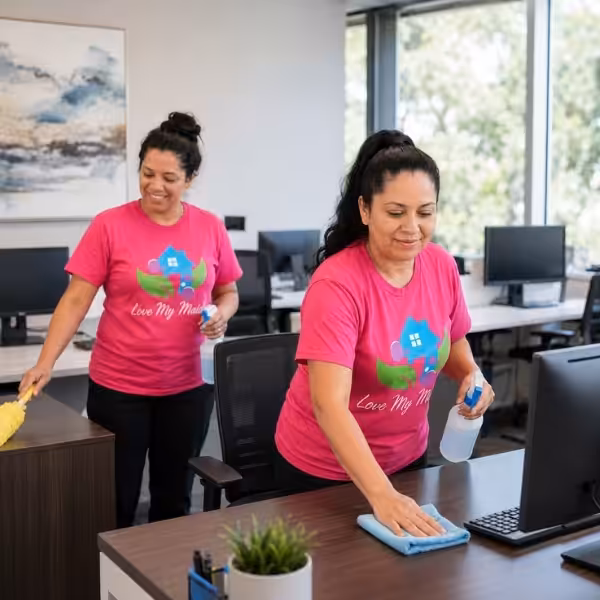 Office cleaner wiping a desk during commercial office cleaning